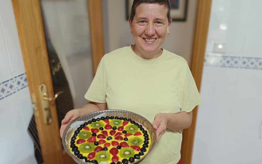 Anaís Isarre, mentora de alegría, sonriendo junto a su tarta mandala vegana de frutas al final de un día de autorregulación PAS.