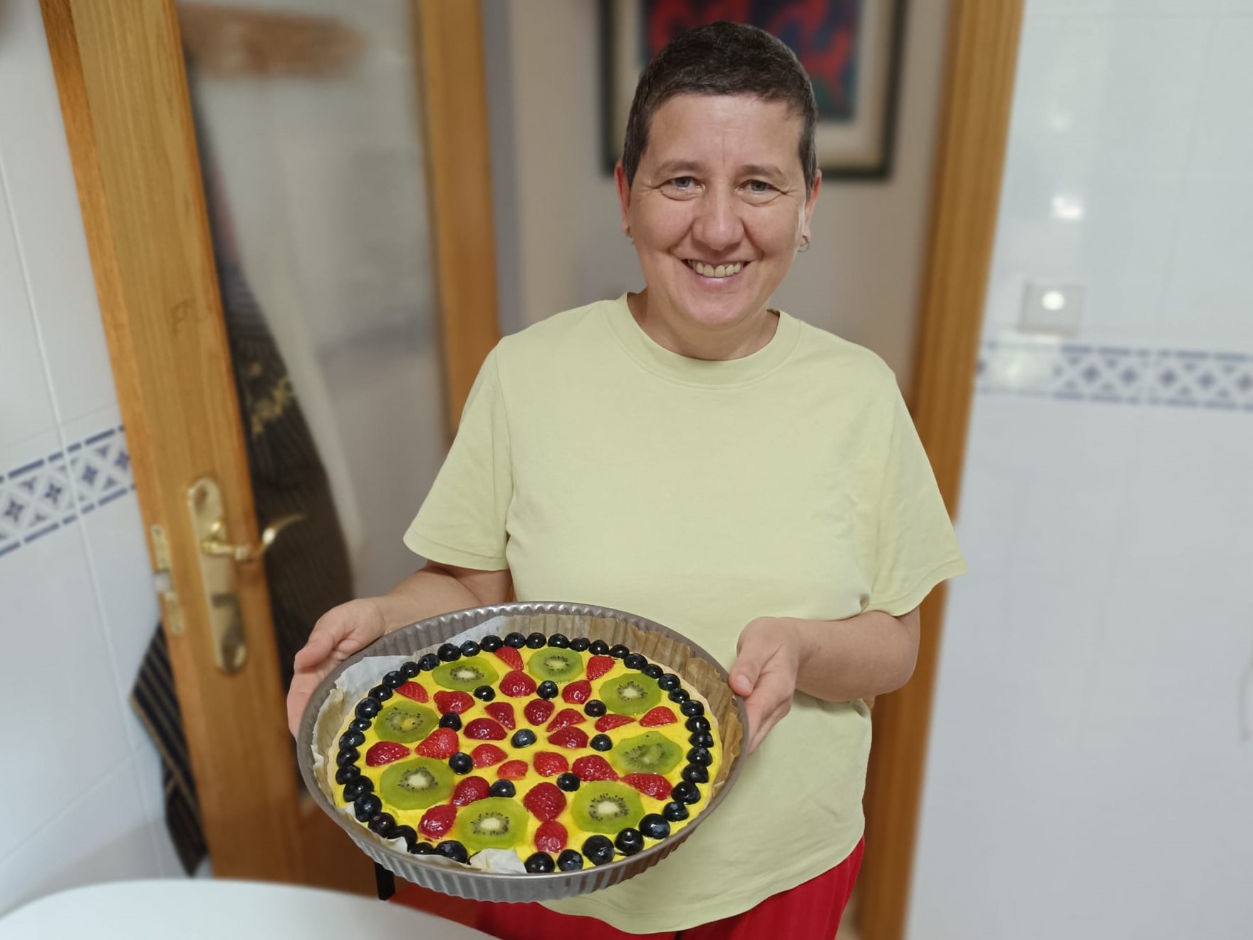 Anaís Isarre, mentora de alegría, sonriendo junto a su tarta mandala vegana de frutas al final de un día de autorregulación PAS.